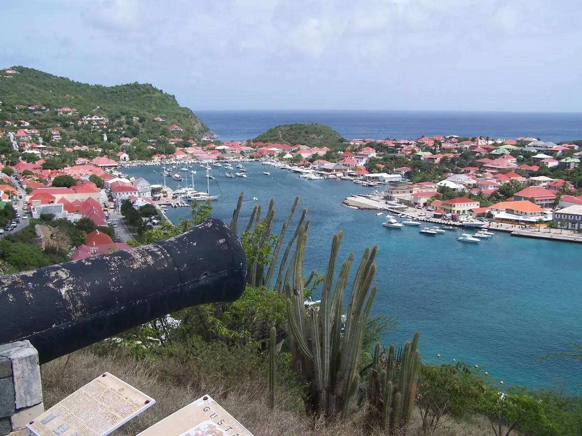 Gustavia Harbour, Saint Barthélemy, with yachts below red-roofed buildings and green hills.